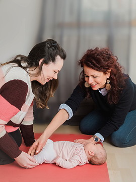 Baby liegend in der Mitte wird von Mutter und Hebamme Anja Maier umsorgt